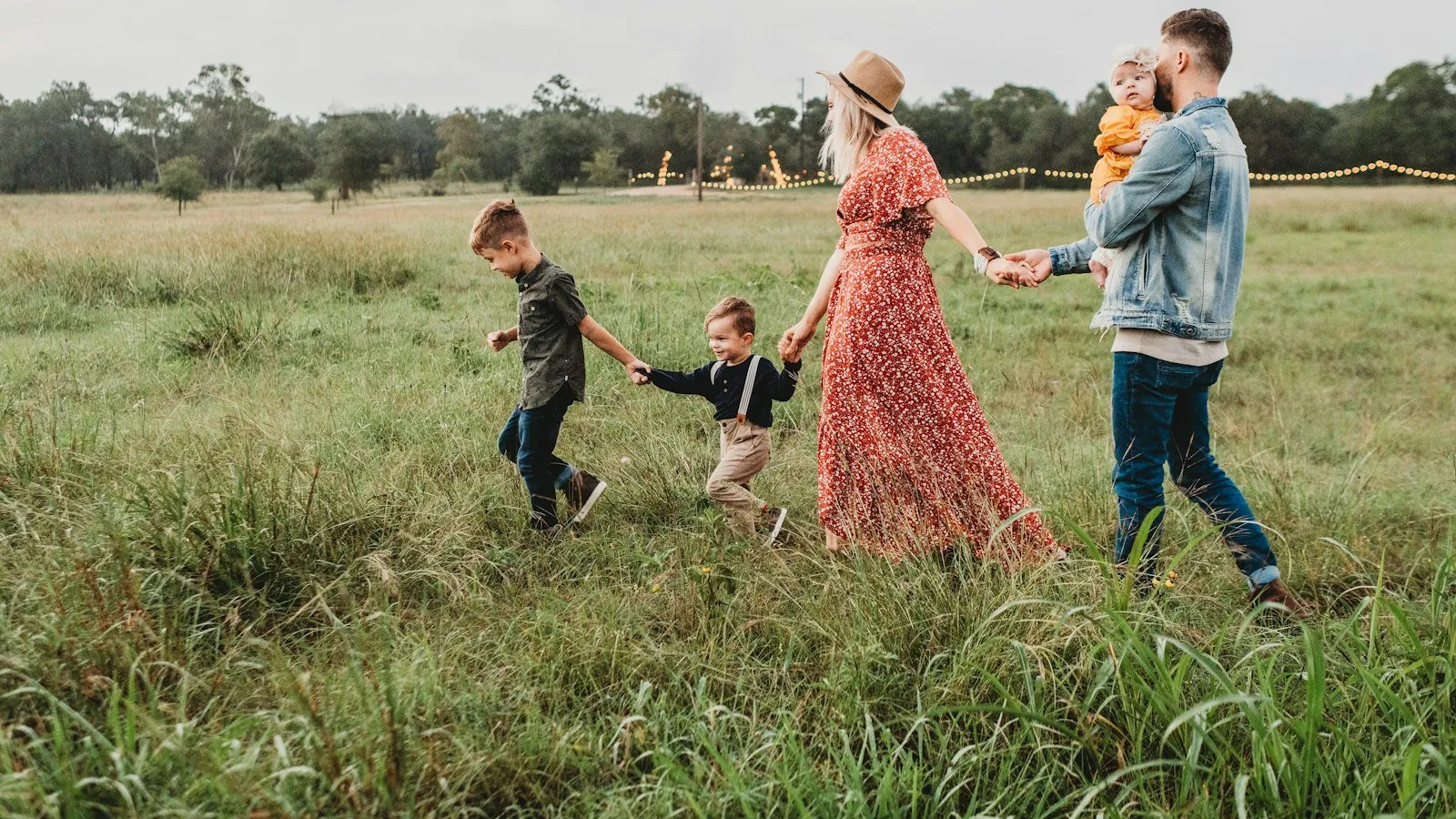 A family walking hand in hand through a grassy meadow