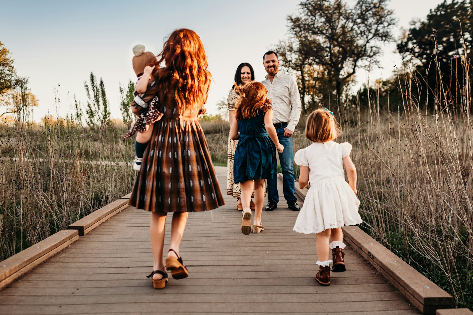 Children running along a boardwalk toward their smiling parents at sunset